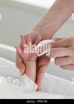 Un nettoyage de la main de bébé avec un coton Banque D'Images