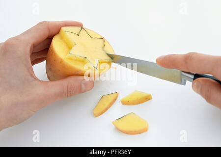 Découper une forme d'étoile d'une pomme de terre pour faire des tirages de pommes de terre Banque D'Images