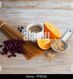 Tasse de café, des tranches d'orange, du riz brun, farine de blé entier (spaghetti) et de haricots rouges Banque D'Images