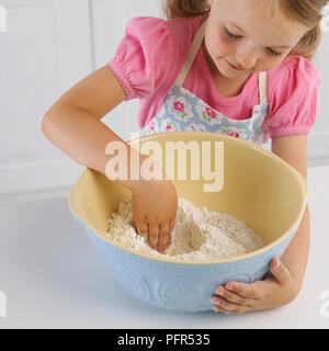 Prendre une fille dans un bol de farine avec sa main, faire du pain, 5 ans Banque D'Images