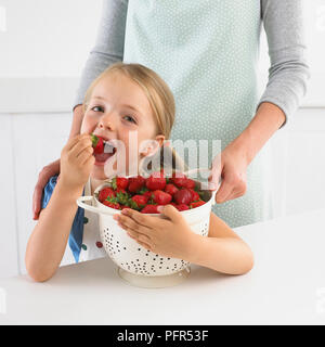 Girl holding passoire de fraises, 5 ans Banque D'Images