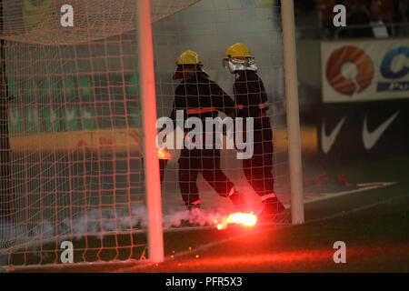 Bucarest, Roumanie - 28 juillet 2018 : Pompier tente d'éteindre les torches jetées sur l'herbe par le Dinamo Bucarest supporters Banque D'Images