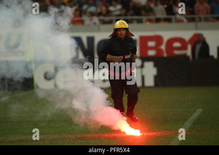 Bucarest, Roumanie - 28 juillet 2018 : Pompier tente d'éteindre les torches jetées sur l'herbe par le Dinamo Bucarest supporters Banque D'Images