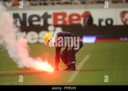 Bucarest, Roumanie - 28 juillet 2018 : Pompier tente d'éteindre les torches jetées sur l'herbe par le Dinamo Bucarest supporters Banque D'Images