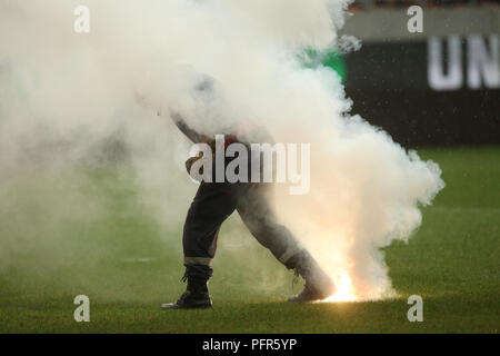 Bucarest, Roumanie - 28 juillet 2018 : Pompier tente d'éteindre les torches jetées sur l'herbe par le Dinamo Bucarest supporters Banque D'Images