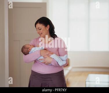 Femme berçant Bébé garçon dans ses bras et souriant Banque D'Images