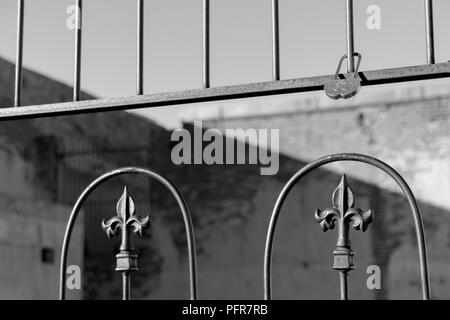 Tourné en noir et blanc d'une forme de cœur verrou sur une clôture de fer avec Fleur de lys sur l'équerrage Banque D'Images