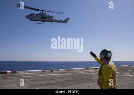 Mer Méditerranée (24 mai 2018) l'Aviation maître de Manœuvre (manutention) 3e classe Lydon Schwartz, de Pittsburgh, rend hommage au pilote d'un Cobra AH-1W, attaché à rotors basculants moyen maritime (VMM) de l'Escadron 162 (renforcée), de l'envol de la San Antonio-classe de transport amphibie Navire dock USS New York (LPD 21) Le 24 mai 2018. New York, homeported à Mayport, en Floride, mène des opérations navales dans la sixième flotte américaine zone d'opérations à l'appui de l'intérêt de la sécurité nationale des États-Unis en Europe et en Afrique. Banque D'Images