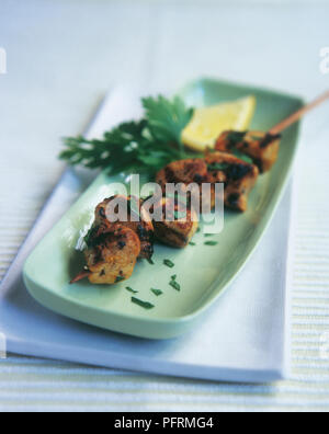 Citron et safran perse (Joojeh kabab brochette de poulet), garni de persil et de tranche de citron vert sur la plaque oblongue Banque D'Images