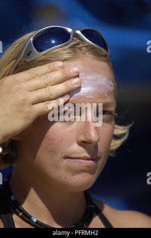 Jeune femme de mettre de la crème solaire sur le front Banque D'Images