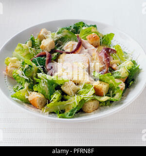 Salade César au poulet servi dans un bol blanc avec des croûtons, d'anchois et parmesan râpé Banque D'Images