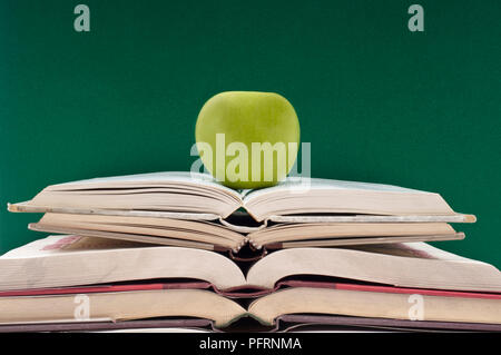 Green Apple sur une pile de livres ouverts Banque D'Images