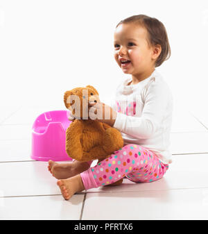 Girl holding soft toy, pot en arrière-plan, 1,5 ans Banque D'Images