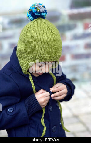 Garçon (6 ans) portant Chapeau tricoté avec bobble et oreilles Banque D'Images