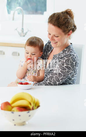 Mère avec bébé manger des fruits (modèle de 18 mois) Banque D'Images