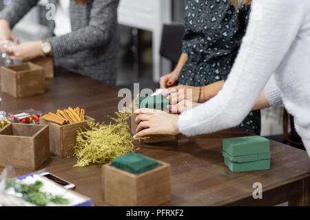 Une femme décore un arrangement de Noël avec des bougies. Mains de près. Master class sur l'apport d'ornements décoratifs. Décoration de Noël avec leurs propres mains. La fête du nouvel an. Flower shop Banque D'Images