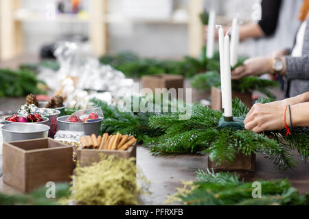 Une femme décore un arrangement de Noël avec des bougies. Mains de près. Master class sur l'apport d'ornements décoratifs. Décoration de Noël avec leurs propres mains. La fête du nouvel an. Flower shop Banque D'Images