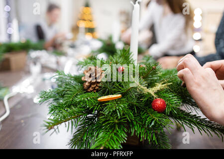 Une femme décore un arrangement de Noël avec des bougies. Mains de près. Master class sur l'apport d'ornements décoratifs. Décoration de Noël avec leurs propres mains. La fête du nouvel an. Flower shop Banque D'Images