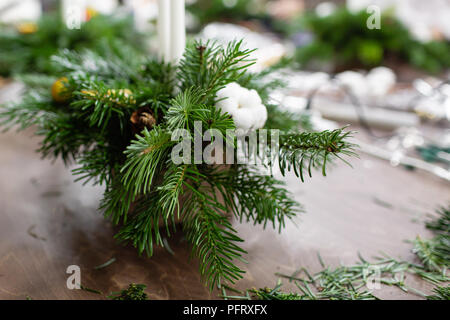 Une femme décore un arrangement de Noël avec des bougies. Mains de près. Master class sur l'apport d'ornements décoratifs. Décoration de Noël avec leurs propres mains. La fête du nouvel an. Flower shop Banque D'Images