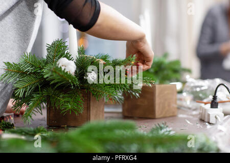 Une femme décore un arrangement de Noël avec des bougies. Mains de près. Master class sur l'apport d'ornements décoratifs. Décoration de Noël avec leurs propres mains. La fête du nouvel an. Flower shop Banque D'Images