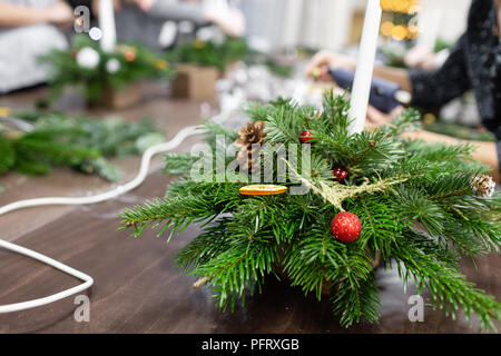 Une femme décore un arrangement de Noël avec des bougies. Mains de près. Master class sur l'apport d'ornements décoratifs. Décoration de Noël avec leurs propres mains. La fête du nouvel an. Flower shop Banque D'Images