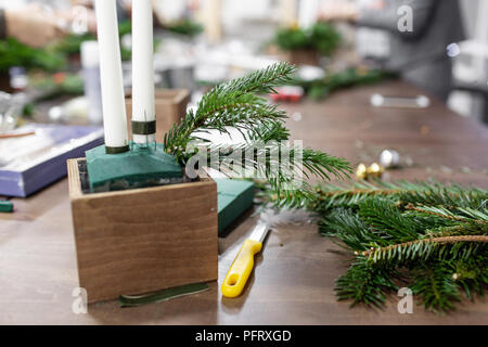 Une femme décore un arrangement de Noël avec des bougies. Mains de près. Master class sur l'apport d'ornements décoratifs. Décoration de Noël avec leurs propres mains. La fête du nouvel an. Flower shop Banque D'Images