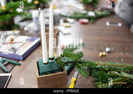 Une femme décore un arrangement de Noël avec des bougies. Mains de près. Master class sur l'apport d'ornements décoratifs. Décoration de Noël avec leurs propres mains. La fête du nouvel an. Flower shop Banque D'Images