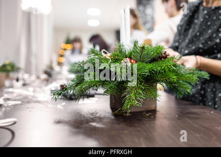 Une femme décore un arrangement de Noël avec des bougies. Mains de près. Master class sur l'apport d'ornements décoratifs. Décoration de Noël avec leurs propres mains. La fête du nouvel an. Flower shop Banque D'Images