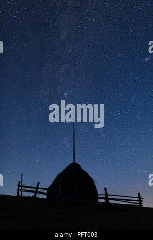 Silhouette d'une pile de paille contre le ciel de nuit avec les étoiles et la Voie lactée visible Banque D'Images