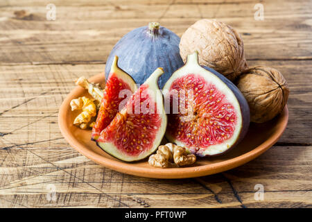 Figues fraîches ensemble et couper des cerneaux de noix sur une plaque l'ancien fond de bois Banque D'Images