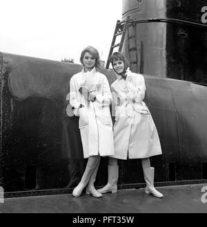 La mode des années 1960. Deux modèles de mode en photo à bord du sous-marin britannique Orpheus. Le sous-marin est ancrée dans le port de Stockholm. Les modèles portent les automnes de la mode d'imperméables. La Suède Mai 1962 Banque D'Images