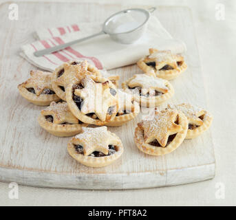 Petits pâtés de Noël avec les étoiles et le sucre à glacer sur le dessus sur la planche à découper en bois Banque D'Images