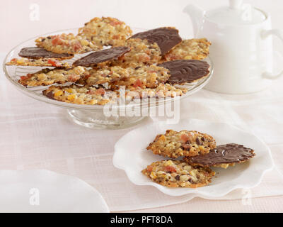 Biscuits florentins avec cerises confites, amandes hachées et peel mixte enrobées de chocolat noir cake stand sur verre et assiette à dessert Banque D'Images