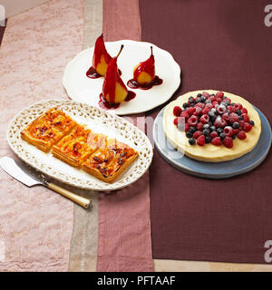 Collection de dessert, tarte aux abricots et amandes galette, confit de poires avec sauce citron cheesecake, surmontées de baies fraîches Banque D'Images