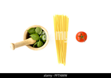 Mortier rempli de feuilles de basilic frais, spaghetti et une tomate sur fond blanc. Les couleurs du drapeau italien. Banque D'Images