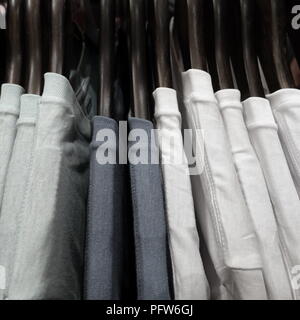 Sélection de blanc et gris mens t shirts accroché à des cintres sur la grille d'une boutique ou magasin de mode Banque D'Images