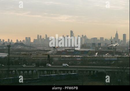 Les voitures roulent à travers une partie industrielle de Newark, New Jersey le matin un ciel voilé à l'heure de pointe, avec l'horizon de Manhattan, New York City dans l'arrière-plan, le 18 mars 2018. () Banque D'Images