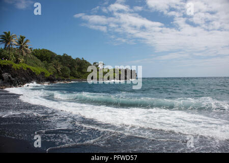 Sur la plage de sable noir Waianapanapa sur l'île de Maui, Hawaii sur une journée ensoleillée. Banque D'Images