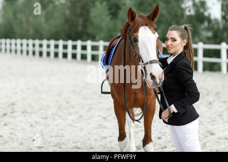 Portrait de femme élégante rider parler à son cheval à l'extérieur. jockey et cheval brun Banque D'Images