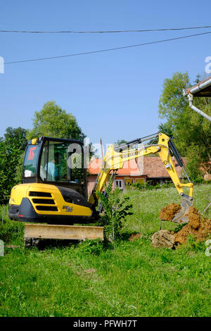 L'homme à l'aide d'une pelle mécanique dans un jardin de creuser une tranchée zala hongrie Banque D'Images