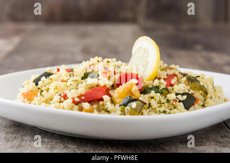 Couscous aux légumes à l'assiette sur la table en bois. Banque D'Images