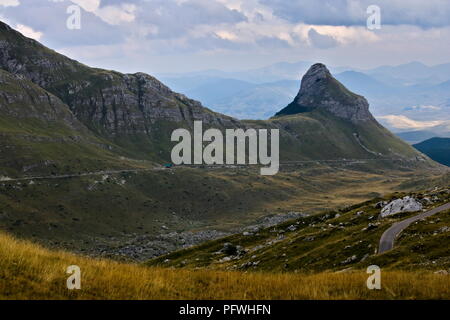 Une route de montagne menant à travers les prés et les collines rocheuses Banque D'Images