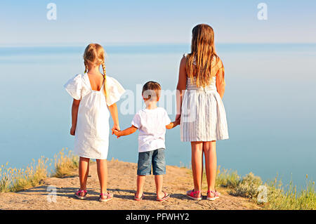 Les enfants se tenant la main par la mer dans la soirée d'été Banque D'Images