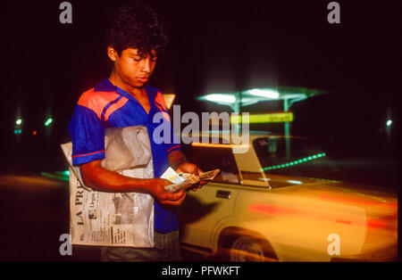 Managua, Nicaragua, élections, Feb 1990 ; un adolescent vendant du quotidien La Prensa de chauffeurs occupés à la jonction de route de nuit. Banque D'Images