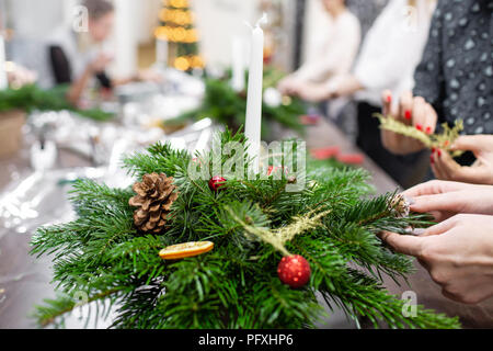 Une femme décore un arrangement de Noël avec des bougies. Mains de près. Master class sur l'apport d'ornements décoratifs. Décoration de Noël avec leurs propres mains. La fête du nouvel an. Flower shop Banque D'Images