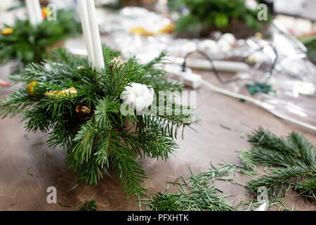 Une femme décore un arrangement de Noël avec des bougies. Mains de près. Master class sur l'apport d'ornements décoratifs. Décoration de Noël avec leurs propres mains. La fête du nouvel an. Flower shop Banque D'Images