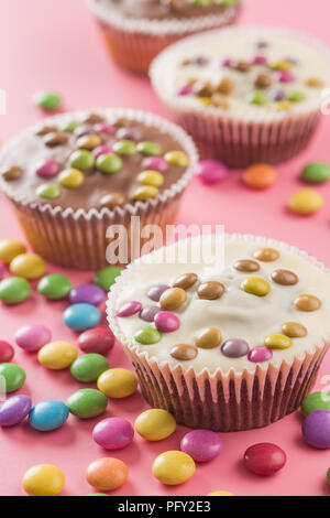 Sweet cupcakes avec des bonbons sur fond rose. Banque D'Images