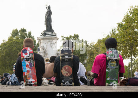 Paris - trois patineurs garçons parisien vu de dos s'appuyant sur leur planche à roulettes sur la Place de la République. La France, l'Europe. Banque D'Images