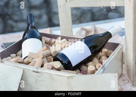 Deux bouteilles de vin rouge dans la vieille boîte en bois plein avec des bouchons sur table. Boire de l'alcool concept de décoration. Close up, selective focus Banque D'Images