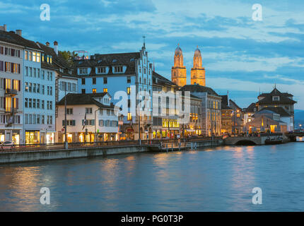 Les bâtiments de la partie historique de la ville de Zurich le long de la rivière Limmat, tours de la cathédrale de Grossmunster au crépuscule Banque D'Images